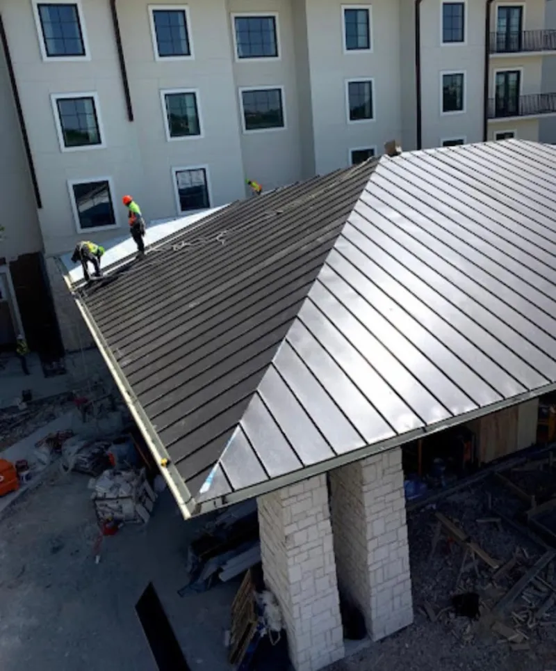 Crew installing standing seam metal roof panels on a commercial project in Windcrest